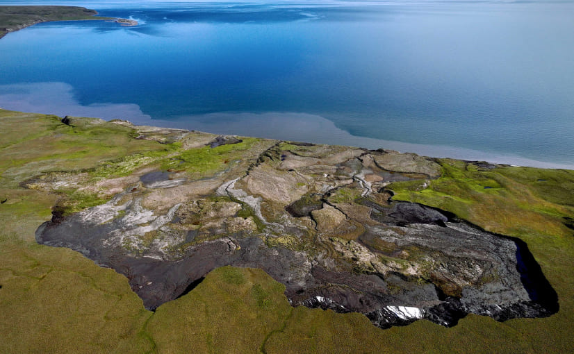 a large body of water sitting next to a lush green hillside